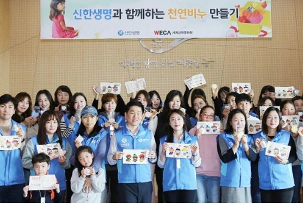 서울 중구에 위치한 신한생명 본사에서 직원봉사자와 가족들이 해외 아동의 질병 예방 지원을 위해 손수 제작한 천연 비누와 파우치를 들고 기념촬영을 하고 있다. 사진=신한생명 제공