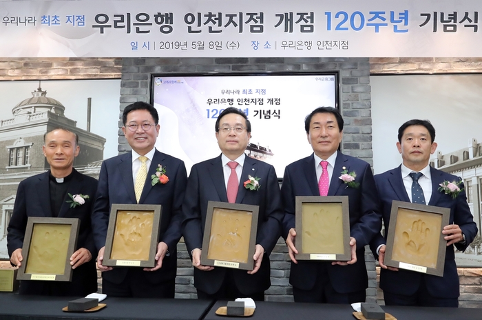우리은행은 지난 8일 인천지점에서 ‘인천지점 개점 120주년 기념행사’를 실시했다. 개점 행사에 참석한 주요인사들이 인천지점의 새로운 출발과 힘찬 도약을 다짐하는 의미에서 본인의 핸드프린팅을 들고 기념사진을 촬영하고 있다. (왼쪽부터 이용권 카톨릭아동청소년재단 이사장(신부), 박남춘 인천시장, 손태승 우리금융그룹회장 겸 우리은행장, 안상수 국회의원, 김영제 NKG 대표이사)